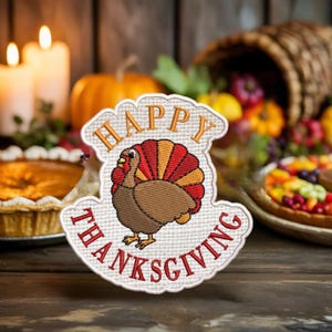 以下が含まれることがあります： 感謝祭をテーマにしたパッチ。漫画の七面鳥が描かれており、赤、オレンジ、黄色の扇形の尾羽があります。「HAPPY THANKSGIVING」の文字が刺繍されています。背景にはパイ、カボチャ、豊穣の角があり、収穫のテーマを連想させます。