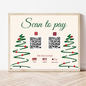 May include: A sign with a Christmas tree design on each side. The sign says "Scan to pay" and has two QR codes. The sign also says "We also accept: Cash, Cards, Apple Pay".