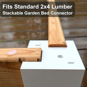 May include: White stackable garden bed connector with a wooden 2x4 lumber piece inserted. The text on the image reads: Fits Standard 2x4 Lumber, Stackable Garden Bed Connector. The connector is designed to fit standard lumber sizes.
