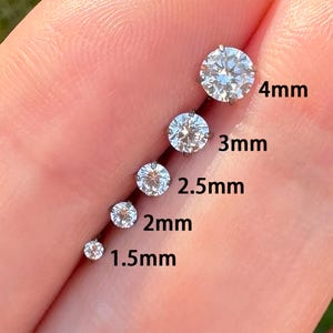 May include: A selection of sparkling diamond stud earrings, ranging in size from 1.5mm to 4mm. Each earring is set in a silver-colored metal. The sizes are labeled in millimeters.