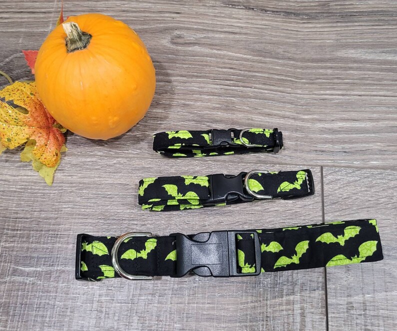 May include: Three black and green dog collars with a bat print. The collars have black plastic buckles and silver D-rings.