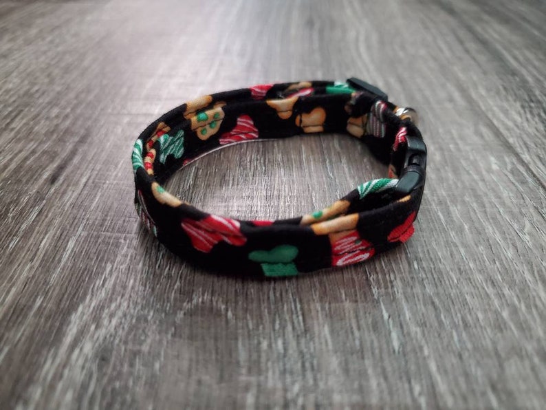 Puede incluir: Un collar ajustable negro con un patr&oacute;n de galletas de jengibre en rojo, verde y marr&oacute;n.