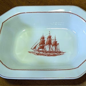 May include: A white octagonal serving bowl with a red rope design around the rim. The bowl features a red and white illustration of a sailing ship in the center.