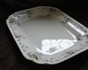 May include: A white ceramic serving platter with a scalloped edge and a floral design in shades of green and yellow.