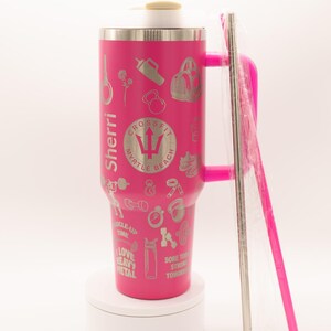Pu&ograve; includere: Un bicchiere termico rosa con manico e cannuccia argentata. Il bicchiere &egrave; decorato con varie icone legate al fitness e il testo "Sherri" e "CrossFit Myrtle Beach". Un involucro di plastica trasparente copre la cannuccia.