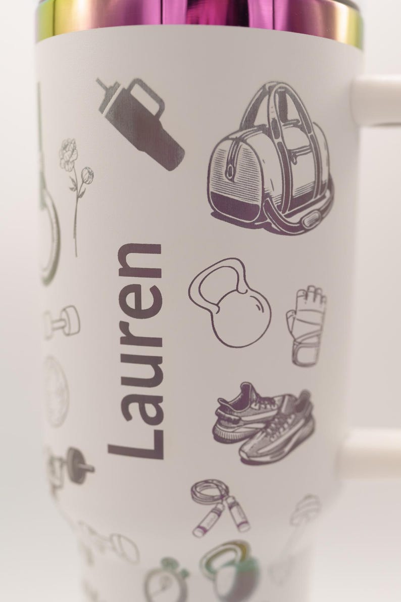Pu&ograve; includere: Tazza da viaggio bianca con bordo arcobaleno e il nome "Lauren" stampato verticalmente. La tazza &egrave; decorata con illustrazioni di attrezzature per il fitness, tra cui una borsa da palestra, un kettlebell e scarpe da ginnastica.