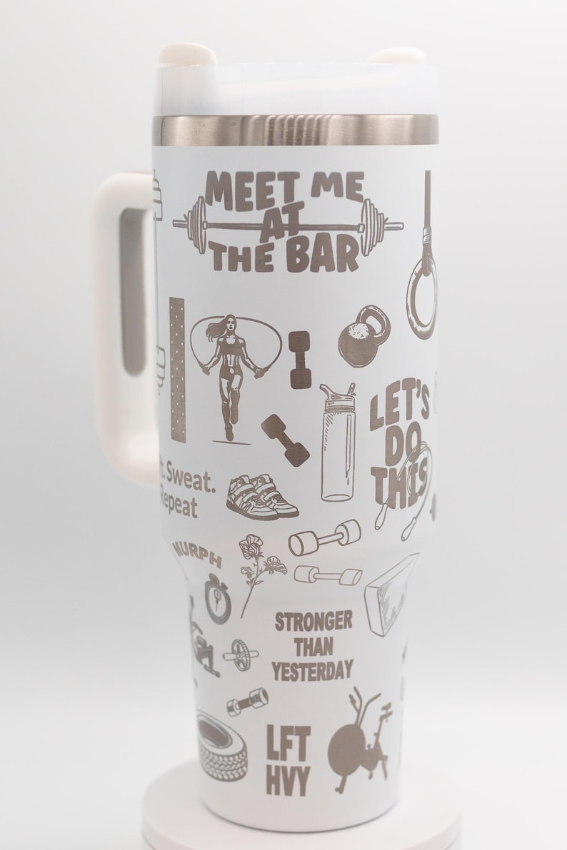 Pu&ograve; includere: Bicchiere termico bianco con manico e coperchio. Il bicchiere &egrave; decorato con grafiche e testo a tema fitness, tra cui "Meet Me at the Bar", una donna che salta la corda, manubri e la frase "Let's Do This".