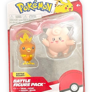 May include: A red and white Pokemon Battle Figure Pack featuring Torchic and Clefairy. The packaging has a Pokeball graphic and the text "Battle Ready!" and "Battle Figure Pack".