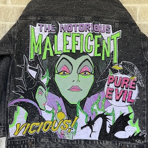 May include: A black denim jacket featuring a large, colorful rhinestone-embellished graphic on the back. The design depicts Maleficent with the text THE NOTORIOUS MALEFICENT, PURE EVIL, and VICIOUS, along with a dragon and a raven illustration.