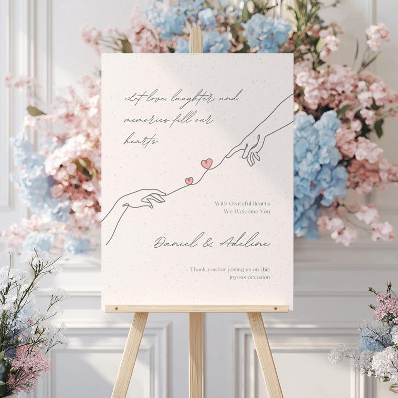 May include: A white sign with a hand-drawn illustration of two hands reaching towards each other with hearts connecting them. The text reads "Let love, laughter, and memories fill our hearts. With grateful hearts, we welcome you. Daniel & Adeline. Thank you for joining us on this joyous occasion."