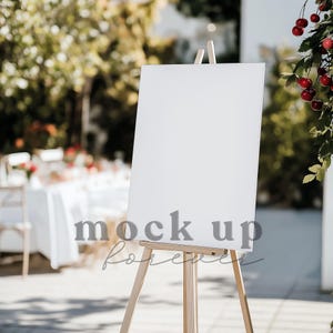 May include: A white blank sign on a wooden easel, standing on a patio with a blurred background of a table setting and greenery.