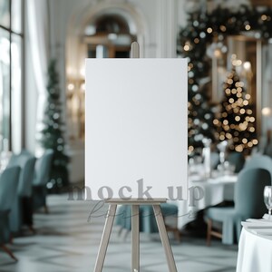 Op de afbeelding: Een houten ezel met een leeg wit canvas, ideaal voor het weergeven van kunstwerken of bewegwijzering. De tekst "mock up forever" is op het canvas gedrukt. De achtergrond toont een wazige restaurantomgeving met kerstversiering.