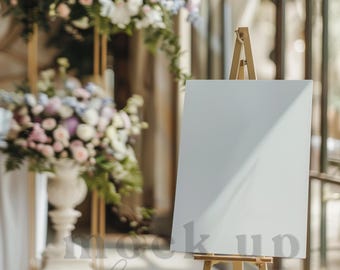 May include: A white blank sign on a wooden easel, standing in front of a floral arrangement. The sign is perfect for displaying messages or announcements.