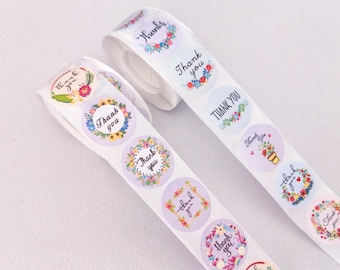 Könnte beinhalten: Zwei Rollen runder Aufkleber mit Blumendesigns und dem Text "Danke" in schwarzer Schrift. Die Aufkleber befinden sich auf weißem Hintergrund.