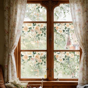 May include: A wooden window with a floral design featuring cream-colored roses and green leaves. The window is framed by floral patterned curtains. The window overlooks a blurred outdoor scene.