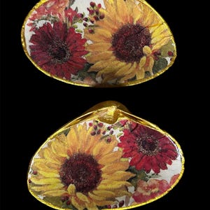 May include: Two golden seashells with a floral design. The shells are decorated with red and yellow flowers, including sunflowers.