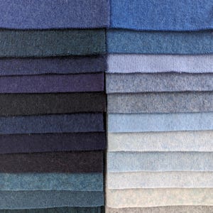 May include: A selection of blue fabric swatches, displayed in columns. The swatches vary in tone, from pale to deep blues, including navy, teal, and light blue. The fabrics have a soft texture, possibly wool or a similar material, with a range of blue hues.