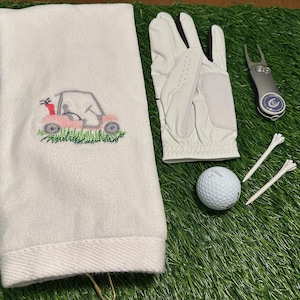Weißes besticktes Golf-Handtuch - Pinkes Golf-Cart auf Gras