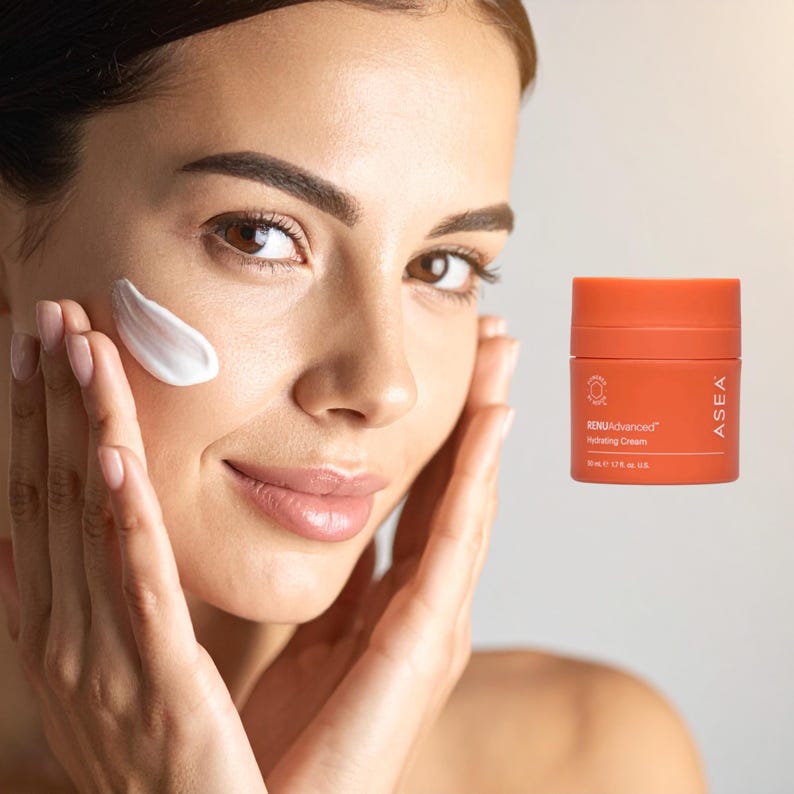 May include: A woman applying white hydrating cream to her face. An orange jar of RENUAdvanced Hydrating Cream is visible. The jar has white text and a logo. The cream is 1.7 fl oz.