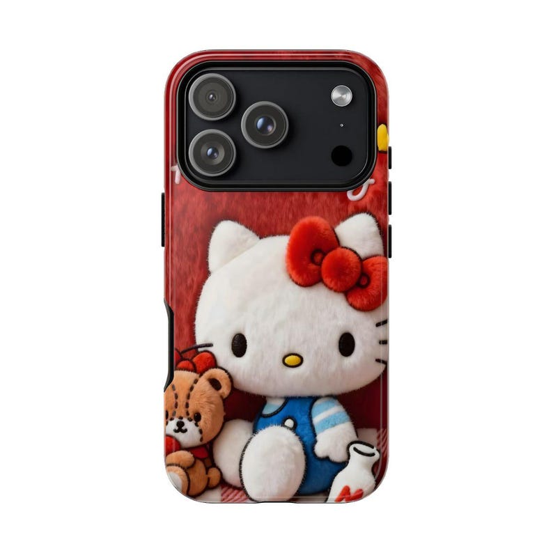 May include: A red phone case featuring a 3D rendering of Hello Kitty with a red bow, blue overalls, and a teddy bear. The case has a textured red background and a glossy finish.