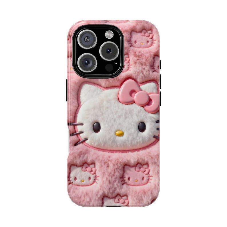 May include: Pink phone case featuring a 3D Hello Kitty design. The case has a fuzzy texture and includes multiple embossed Hello Kitty faces and bows. The phone's camera lenses are visible at the top.