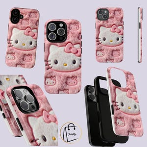 May include: Pink phone cases featuring a Hello Kitty design. The cases have a textured, plush appearance with a large Hello Kitty face and bow, surrounded by smaller Hello Kitty images. The cases are designed to fit various phone models.