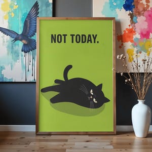 以下が含まれることがあります： 緑色の背景に黒猫が描かれたフレーム入りアートプリント。「NOT TODAY.」の文字が黒色で印刷されています。フレームは薄茶色です。インテリア装飾。