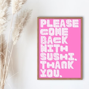 以下が含まれることがあります： 鮮やかなピンク色の背景に「PLEASE COME BACK WITH SUSHI. THANK YOU.」と白い文字で書かれた額入りのプリント。木製のフレームに入っており、白い壁にドライフラワーと一緒に飾られています。