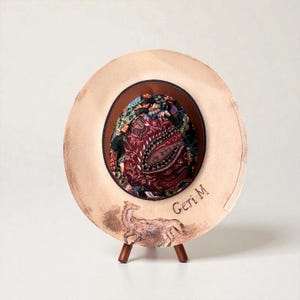 May include: A wide-brimmed beige hat featuring a hand-painted brown fox illustration on the brim, the text Geri M, and a dark brown leather band. The interior crown is lined with a vibrant, multi-coloured fabric displaying a complex floral and paisley pattern.