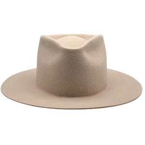 May include: A beige fedora hat with a wide brim. The hat has a structured crown and a rounded top. The hat is made of a soft material and is a neutral color. This hat is a stylish accessory.
