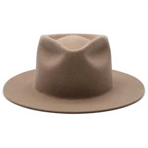 May include: A tan fedora hat with a wide brim. The hat has a pinched crown and a structured shape. The hat is made of a soft material and is suitable for various occasions. The hat's brim measures approximately 3 inches.