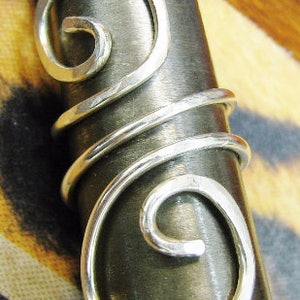 May include: Silver hammered double wrap ring with a swirl design. The ring is shown on a wooden surface.