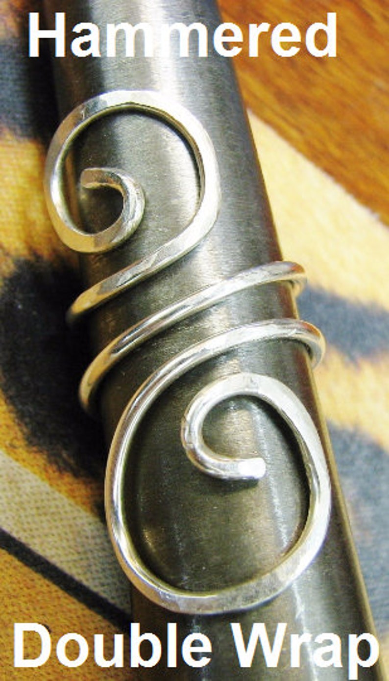 May include: Silver hammered double wrap ring with a swirl design. The ring is shown on a wooden surface.