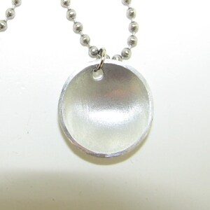 May include: A silver necklace with a round, smooth pendant. The pendant has a small hole at the top for attaching the chain.