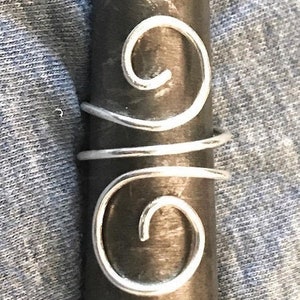 May include: Silver double wrap hair ring with a round, smooth design. The ring is made of wire and has two spirals.