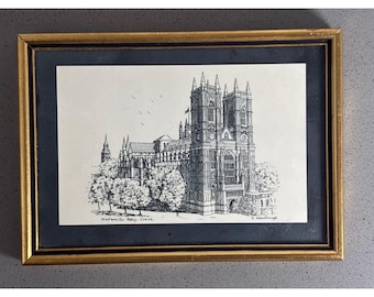 以下が含まれることがあります： ロンドンのウェストミンスター寺院を描いた白黒のインク画。詳細な建築の線と木々が描かれ、黒いマット付きの金色のフレームに収められています。下部には「Westminster Abbey, London」という文字が印刷されています。