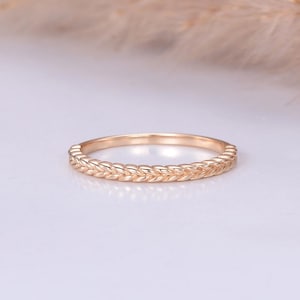 May include: A delicate gold band ring with a braided design. The ring is simple and elegant, perfect for a wedding band or a promise ring.