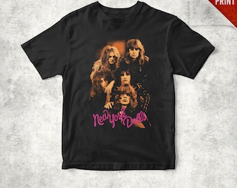 May include: Black t-shirt featuring a vintage-style image of the band New York Dolls. The image is in shades of orange and brown, with the band's name in pink script. The shirt has a classic crew neck and short sleeves.
