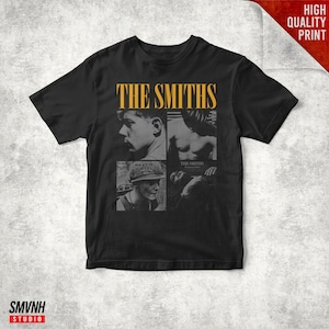 May include: Black t-shirt featuring the band name "THE SMITHS" in yellow block letters above a collage of four black and white images. The shirt has a crew neck and short sleeves. The words "HIGH QUALITY PRINT" are in the top right corner.