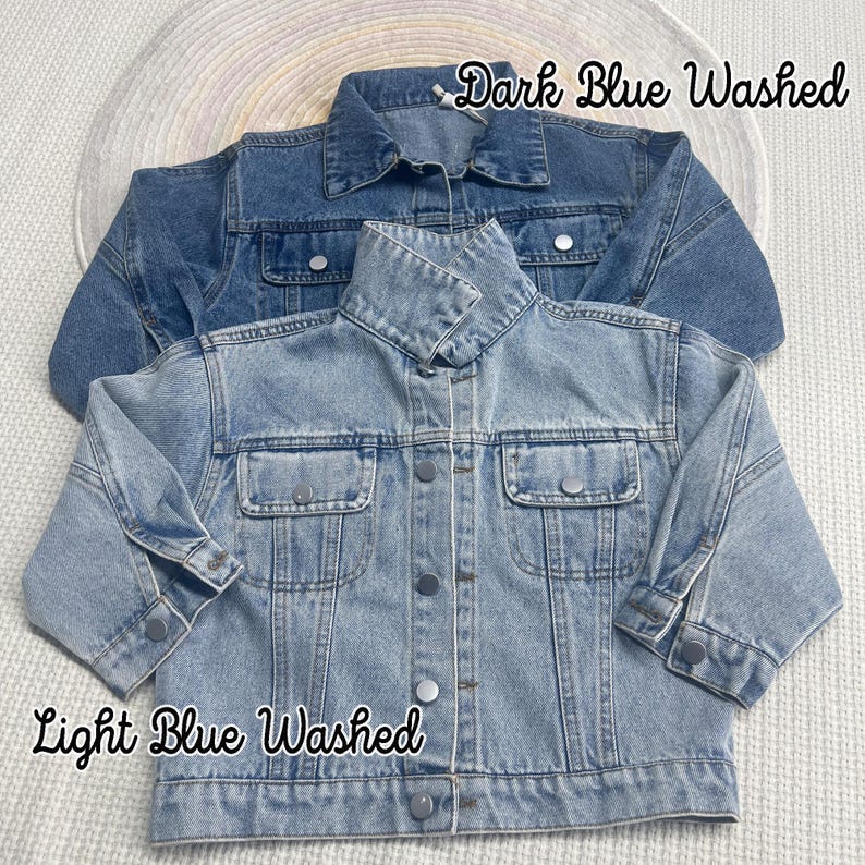May include: Two denim jackets, one light blue washed and one dark blue washed. The jackets are laid out on a white surface.