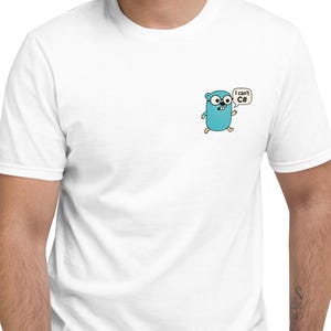 May include: A white short-sleeved t-shirt featuring a small graphic on the left chest of a light blue cartoon character with a speech bubble containing the text I can't C#. The shirt has a crew neckline and a standard fit.