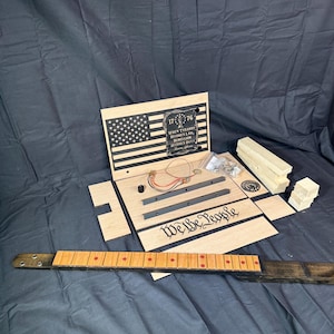 May include: A wooden kit for building a guitar with an American flag design and the text "1776 When Tyranny Becomes Law, Rebellion Becomes Duty." The kit also includes a fretboard with red dots and the text "We the People".