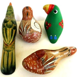 May include: Four handcrafted bird figurines. One is a tall, green and yellow parrot. Two are brown and white painted bird-shaped ornaments. The fourth is a brown and tan bird-shaped whistle. These decorative items are likely made of wood or ceramic.