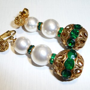May include: Gold tone clip-on earrings with two white pearl beads and a green rhinestone ball.