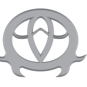 Puede incluir: Un símbolo de metal plateado con un diseño estilizado que se asemeja a una flor o una estrella. El símbolo es circular con un borde puntiagudo y dentado.