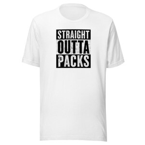 May include: A white short-sleeved t-shirt featuring a black rectangular graphic on the chest. The graphic contains the distressed white text "STRAIGHT" on the top line, "OUTTA" on the middle line, and "PACKS" on the bottom line in a bold font.