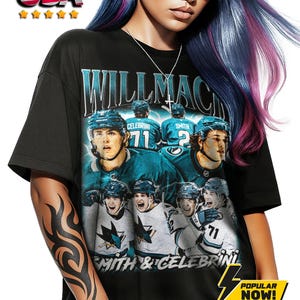 Könnte beinhalten: Schwarzes Grafik-T-Shirt mit Eishockeyspielern und dem Text "WILLMACH" und "SMITH & CELEBRINI". Das Design enthält teal- und weiße Farben. Das Shirt hat eine "POPULAR NOW!" Grafik.