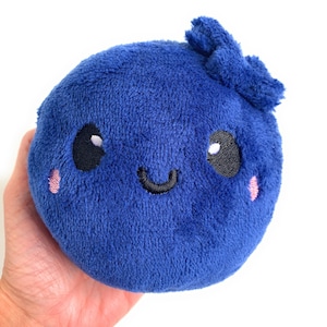 May include: A plush blue blueberry with a happy face, embroidered eyes, and a pink bow on top.