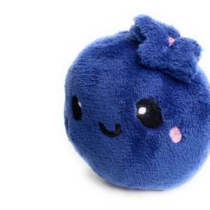 May include: A plush blue blueberry with a smiling face and a small pink flower on top.