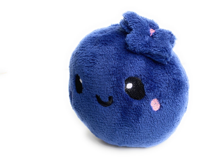 May include: A plush blue blueberry with a smiling face and a small pink flower on top.